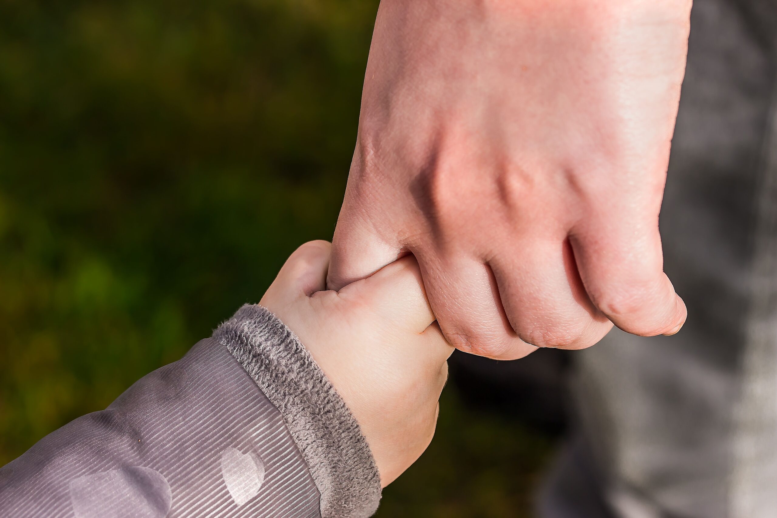 An adult holding a child's hand
